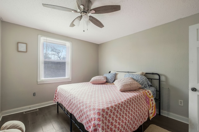 bedroom with ceiling fan, dark hardwood / wood-style flooring, and a textured ceiling