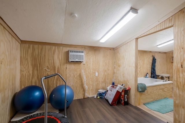 workout area with a textured ceiling, wooden walls, wood-type flooring, and a wall mounted air conditioner