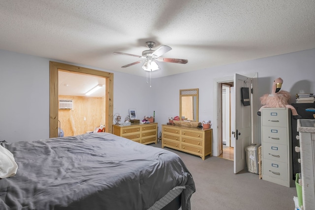 bedroom with an AC wall unit, ceiling fan, light colored carpet, and a textured ceiling