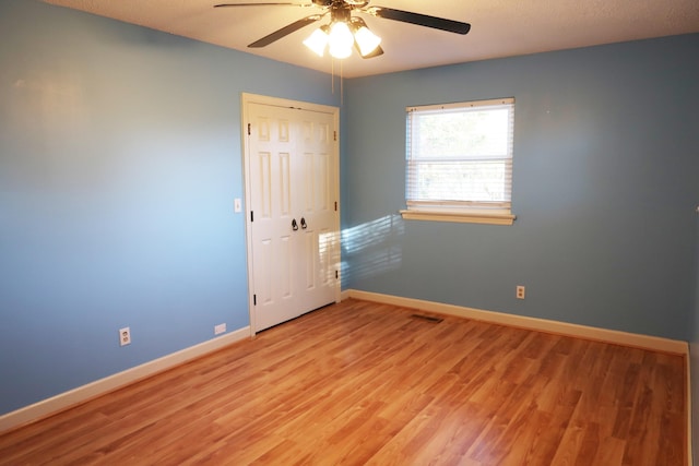 empty room with a textured ceiling, light wood-type flooring, and ceiling fan