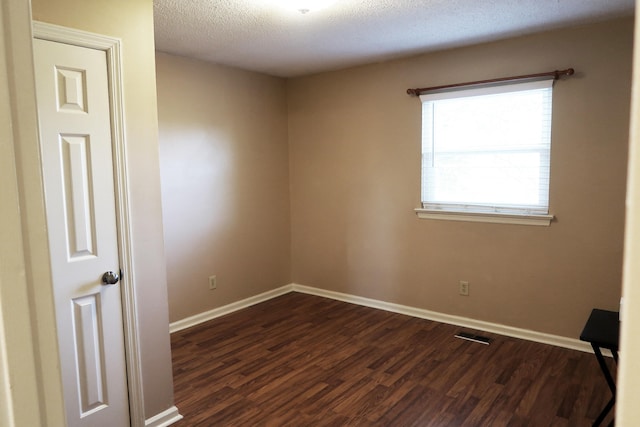 spare room featuring a textured ceiling and dark wood-type flooring