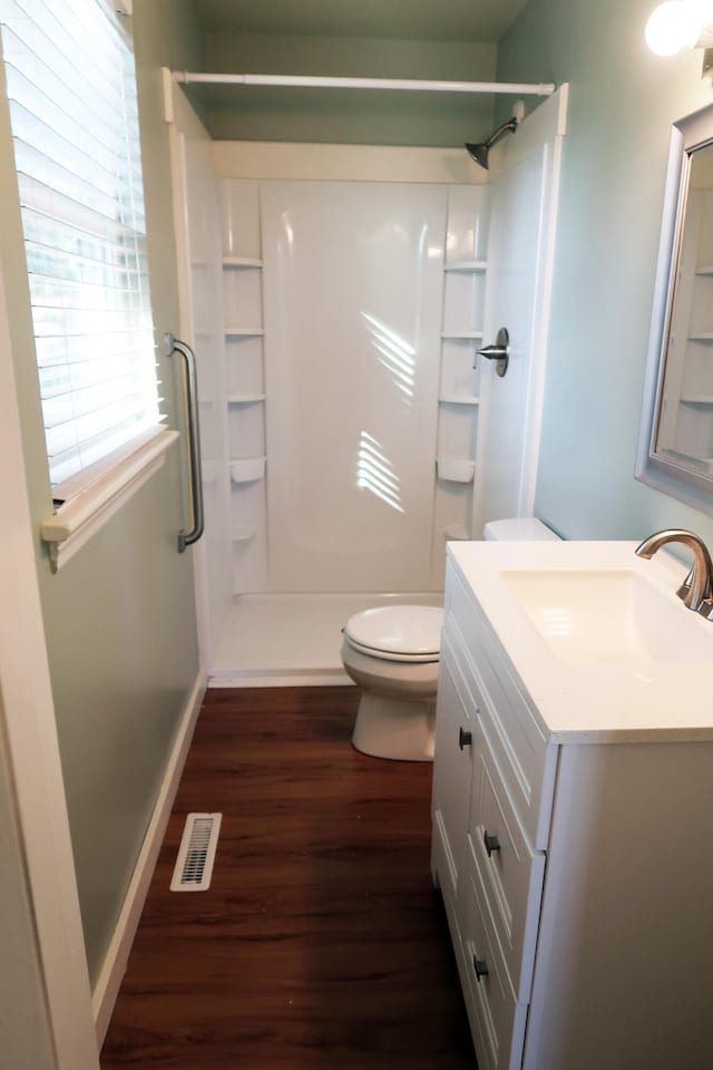 bathroom with wood-type flooring, vanity, toilet, and walk in shower