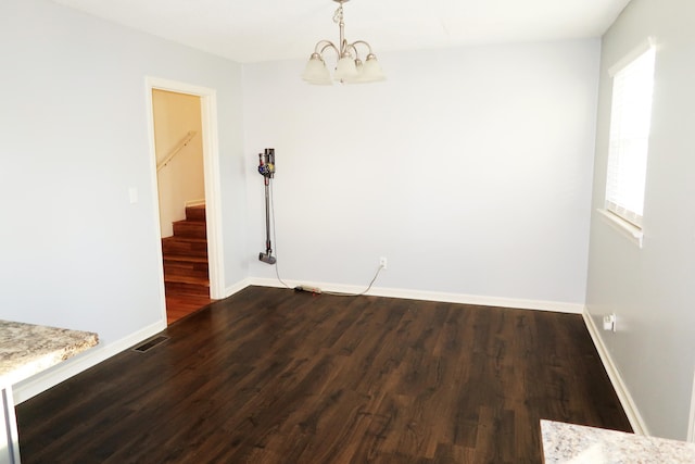 unfurnished dining area featuring an inviting chandelier and dark wood-type flooring