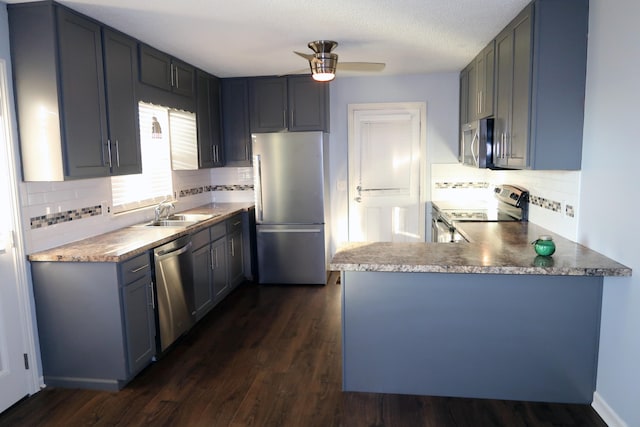 kitchen featuring appliances with stainless steel finishes, dark hardwood / wood-style flooring, backsplash, ceiling fan, and sink