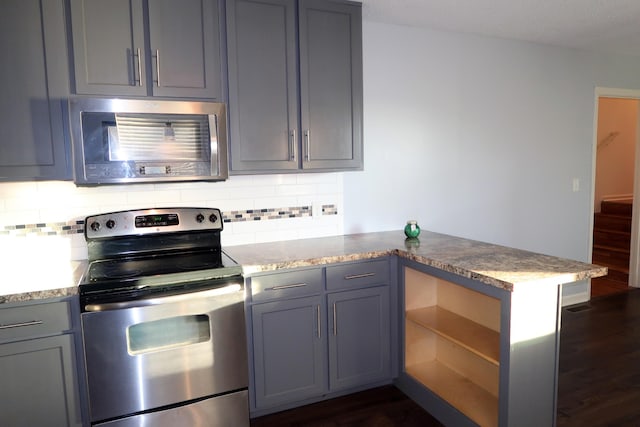 kitchen featuring kitchen peninsula, appliances with stainless steel finishes, dark hardwood / wood-style flooring, tasteful backsplash, and gray cabinets