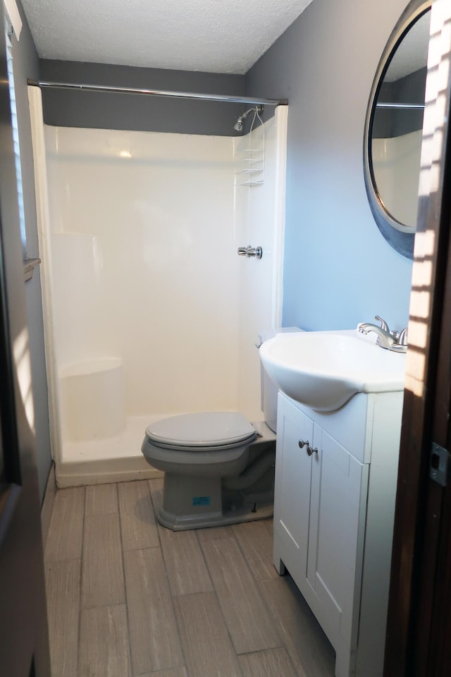 bathroom with a textured ceiling, vanity, hardwood / wood-style flooring, and walk in shower