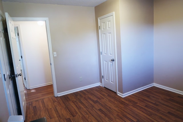 unfurnished bedroom featuring a textured ceiling, a closet, and dark hardwood / wood-style floors