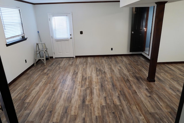 empty room featuring ornamental molding and dark wood-type flooring