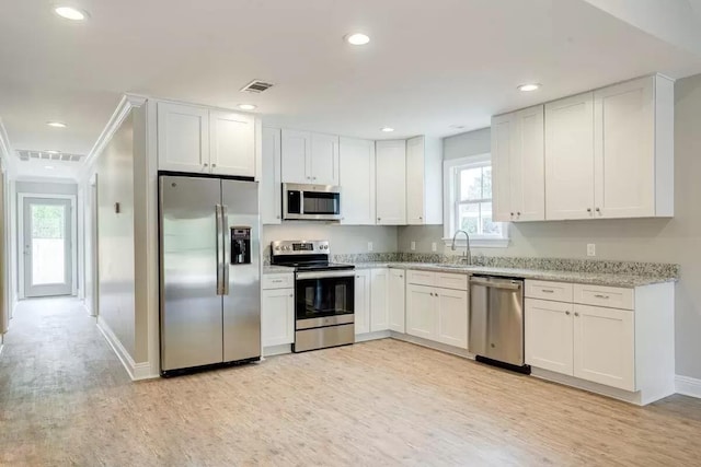 kitchen featuring sink, light hardwood / wood-style flooring, light stone counters, white cabinetry, and stainless steel appliances