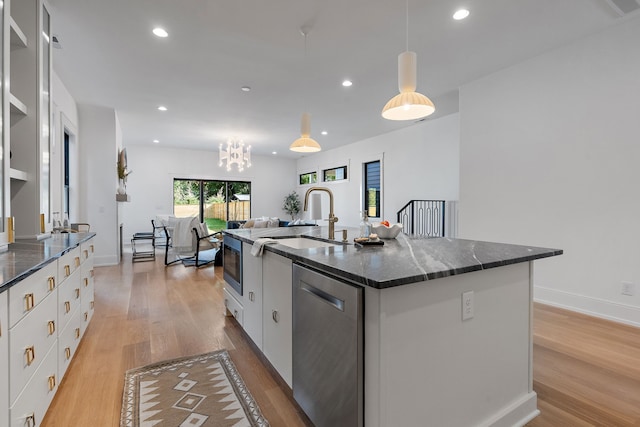 kitchen with white cabinets, an island with sink, light wood-type flooring, and appliances with stainless steel finishes