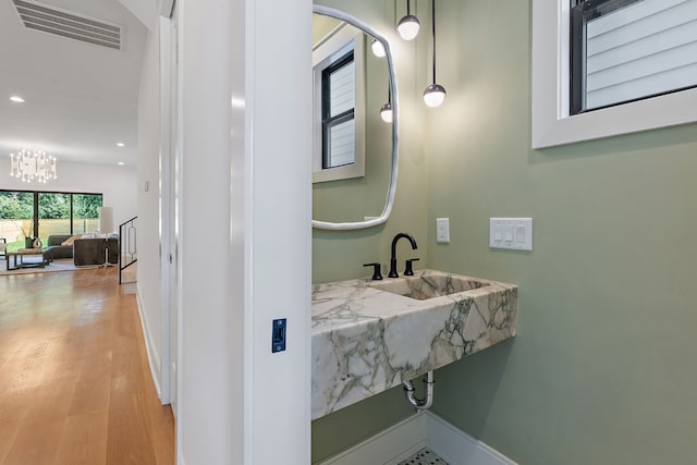 bathroom with hardwood / wood-style flooring, sink, and an inviting chandelier