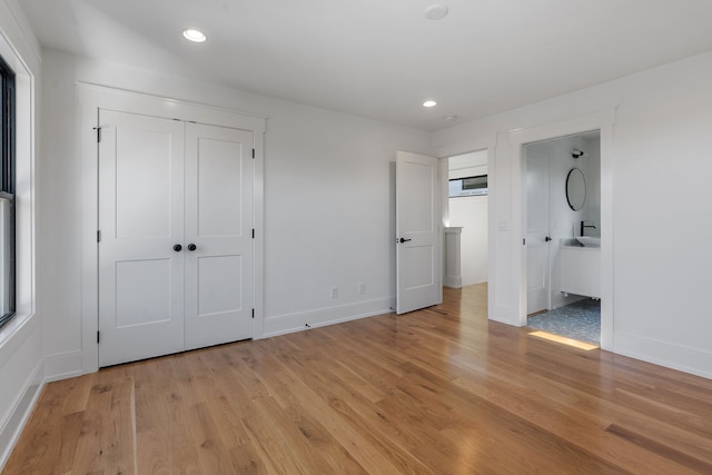 unfurnished bedroom featuring ensuite bathroom and light hardwood / wood-style flooring