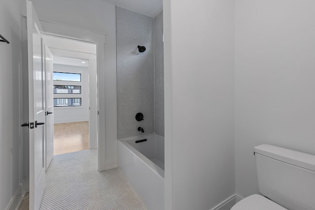 bathroom with tile patterned flooring, tiled shower / bath combo, and toilet