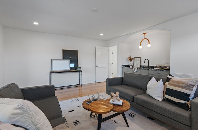 living room featuring sink, a chandelier, and light wood-type flooring