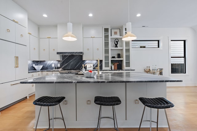 kitchen featuring white cabinets, a kitchen breakfast bar, white built in refrigerator, and decorative light fixtures