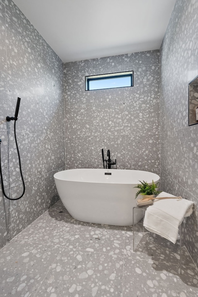 bathroom featuring a tub to relax in and tile walls