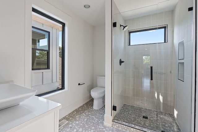 bathroom featuring tile patterned floors, vanity, toilet, and a shower with door