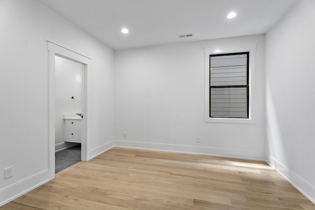 unfurnished bedroom featuring ensuite bath and light hardwood / wood-style flooring