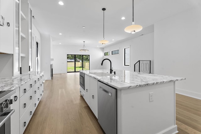 kitchen featuring appliances with stainless steel finishes, sink, white cabinets, hanging light fixtures, and a kitchen island with sink