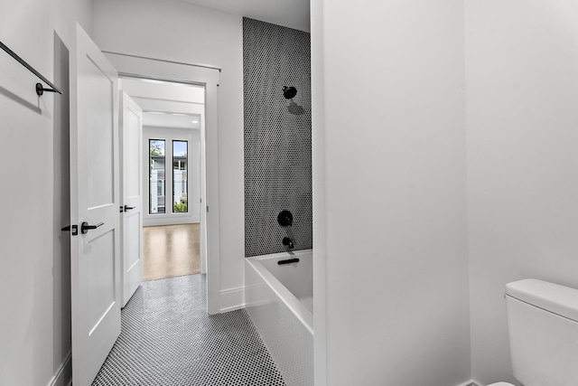 bathroom featuring tiled shower / bath, tile patterned floors, and toilet