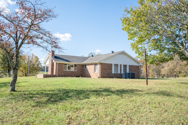 ranch-style home with central air condition unit and a front lawn