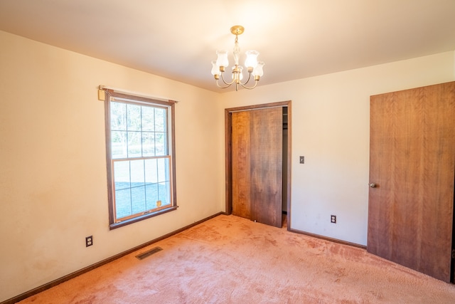 unfurnished bedroom with light colored carpet, an inviting chandelier, and a closet