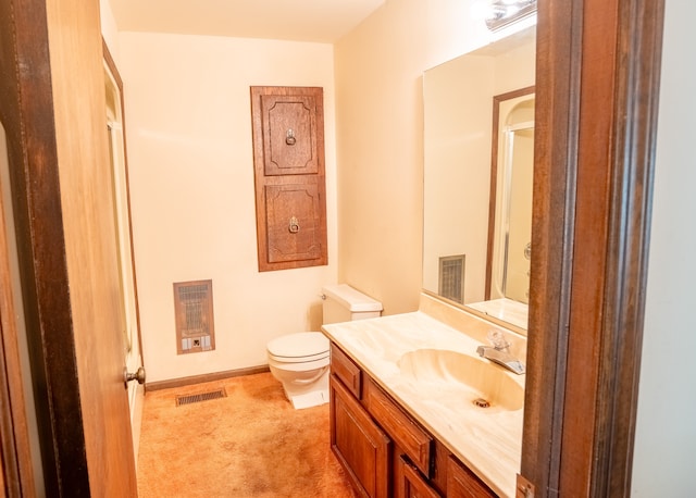 bathroom with vanity, heating unit, and toilet