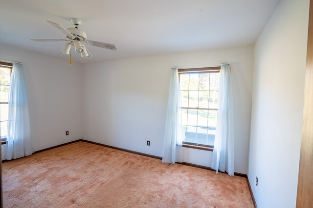 carpeted spare room featuring ceiling fan and plenty of natural light