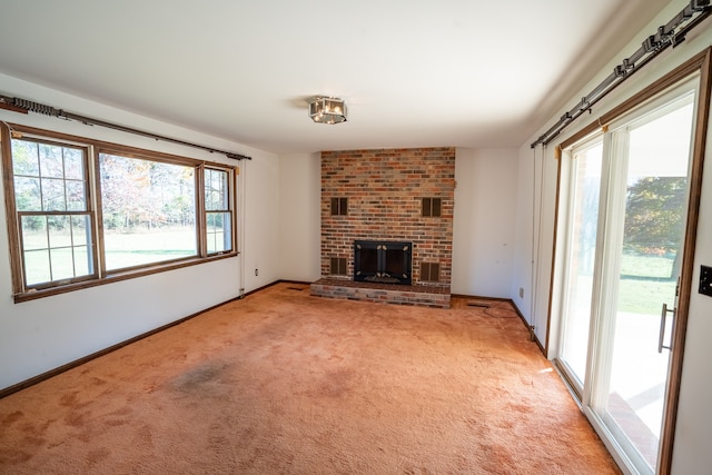 unfurnished living room with plenty of natural light, carpet, and a brick fireplace