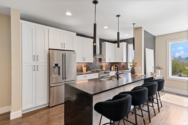 kitchen with dark hardwood / wood-style flooring, white cabinetry, stainless steel appliances, and a kitchen island with sink