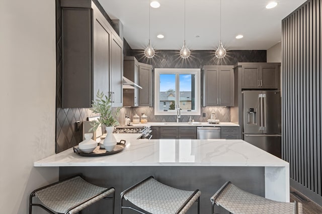 kitchen with pendant lighting, backsplash, a kitchen breakfast bar, appliances with stainless steel finishes, and kitchen peninsula