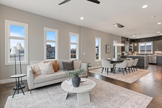 living room featuring ceiling fan with notable chandelier and dark hardwood / wood-style flooring