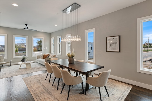 dining space featuring ceiling fan with notable chandelier and dark hardwood / wood-style flooring