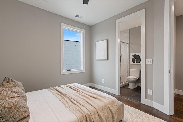 bedroom featuring dark hardwood / wood-style floors, ceiling fan, and ensuite bath