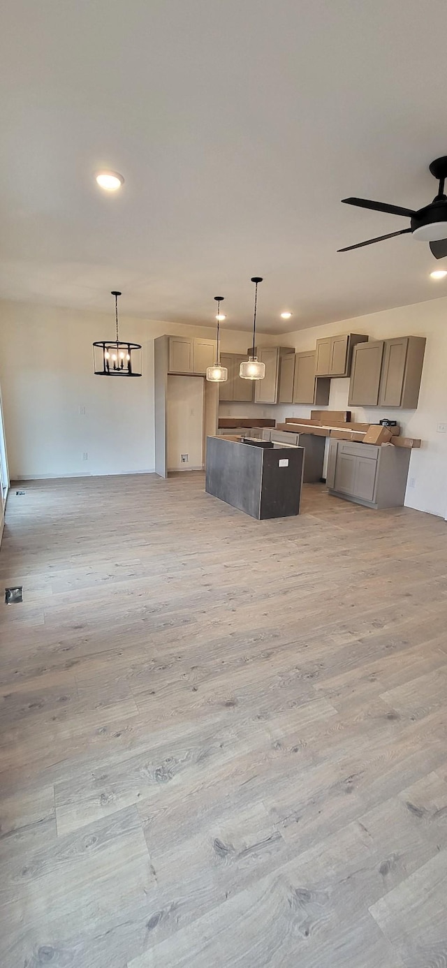 kitchen featuring gray cabinets, ceiling fan with notable chandelier, pendant lighting, and light hardwood / wood-style flooring