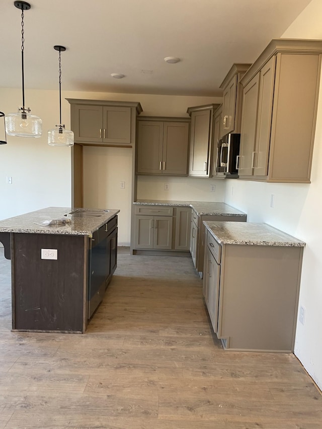 kitchen with gray cabinetry, light wood-type flooring, a kitchen island, pendant lighting, and light stone countertops