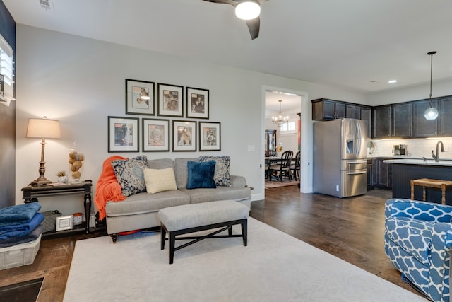 living room with ceiling fan with notable chandelier, dark hardwood / wood-style flooring, and sink