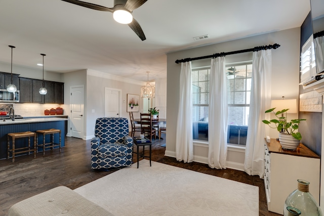 living room featuring sink, ceiling fan with notable chandelier, dark hardwood / wood-style flooring, and crown molding