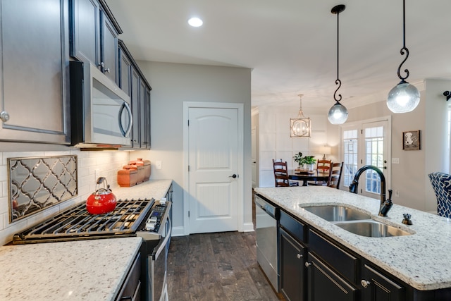 kitchen with sink, stainless steel appliances, dark hardwood / wood-style floors, pendant lighting, and a center island with sink