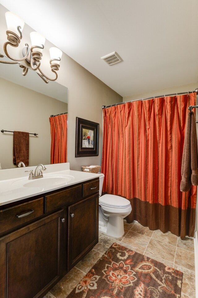 bathroom featuring a notable chandelier, vanity, and toilet