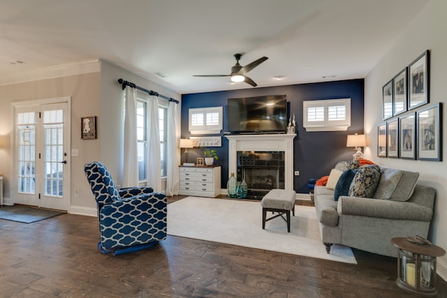 living room featuring a tile fireplace, ceiling fan, a healthy amount of sunlight, and dark hardwood / wood-style floors