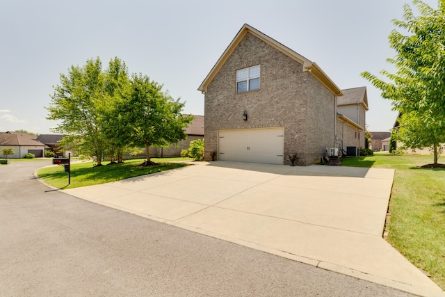 view of side of property with central air condition unit, a garage, and a lawn