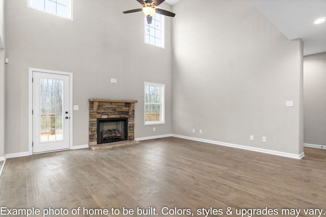 unfurnished living room with a fireplace, a wealth of natural light, hardwood / wood-style floors, and a high ceiling