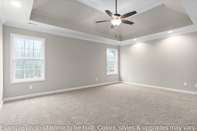 carpeted spare room featuring ornamental molding, plenty of natural light, ceiling fan, and a tray ceiling