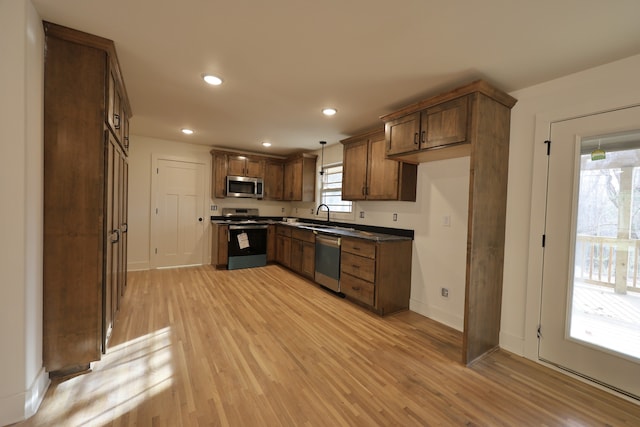 kitchen featuring decorative light fixtures, sink, light wood-type flooring, and stainless steel appliances