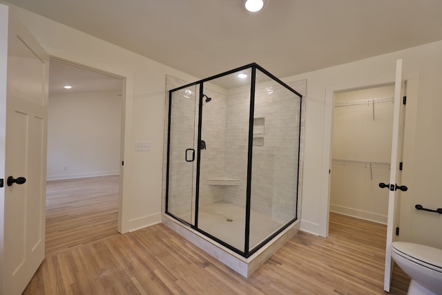 bathroom featuring hardwood / wood-style flooring, toilet, and a shower with door