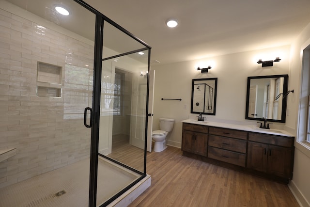 bathroom with wood-type flooring, vanity, toilet, and a shower with door