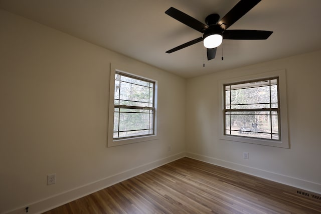 unfurnished room featuring wood-type flooring, a wealth of natural light, and ceiling fan