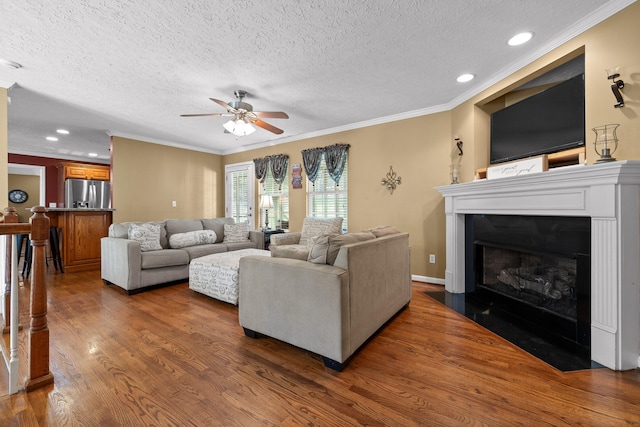 living room featuring ceiling fan, dark wood-type flooring, a textured ceiling, and ornamental molding