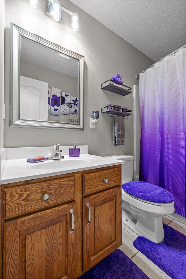 bathroom with tile patterned floors, vanity, a textured ceiling, and toilet